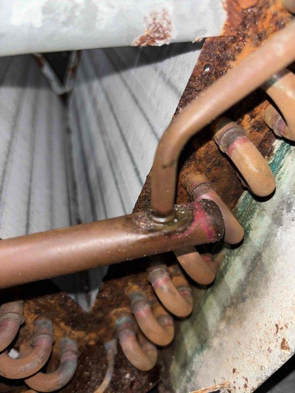 # NC-No Cool Service Completed

Responded to no cooling complaint with outdoor unit running and thermostat set to 76°F but reading 78°F. Upon inspection, discovered extensive corrosion and rust throughout the refrigerant line connections and valve assembly. Copper piping exhibited significant oxidation with green patina formation, and connection points showed heavy corrosion buildup indicating prolonged moisture exposure. The evaporator coil displayed discoloration and oxidation across multiple copper tube loops. Metal mounting surfaces and galvanized brackets exhibited severe rust deterioration with mineral deposits and scaling. The advanced corrosion at pipe joints and valve assembly compromised system integrity and refrigerant flow. Documented equipment condition with photos showing deteriorated copper lines, corroded coil sections, and rusted connection hardware. System requires immediate attention to address corrosion-related refrigerant leaks and component failure to restore prop