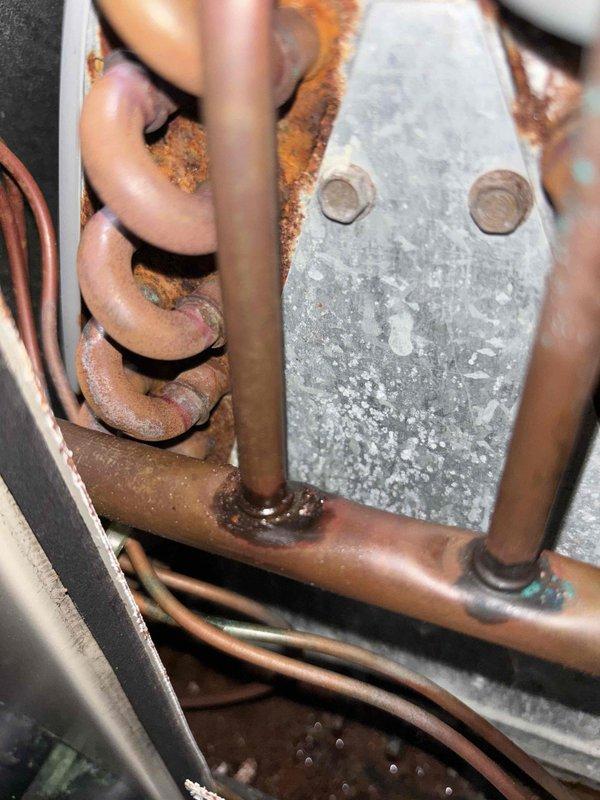 # NC-No Cool Service Completed

Responded to no cooling complaint with outdoor unit running and thermostat set to 76°F but reading 78°F. Upon inspection, discovered extensive corrosion and rust throughout the refrigerant line connections and valve assembly. Copper piping exhibited significant oxidation with green patina formation, and connection points showed heavy corrosion buildup indicating prolonged moisture exposure. The evaporator coil displayed discoloration and oxidation across multiple copper tube loops. Metal mounting surfaces and galvanized brackets exhibited severe rust deterioration with mineral deposits and scaling. The advanced corrosion at pipe joints and valve assembly compromised system integrity and refrigerant flow. Documented equipment condition with photos showing deteriorated copper lines, corroded coil sections, and rusted connection hardware. System requires immediate attention to address corrosion-related refrigerant leaks and component failure to restore prop