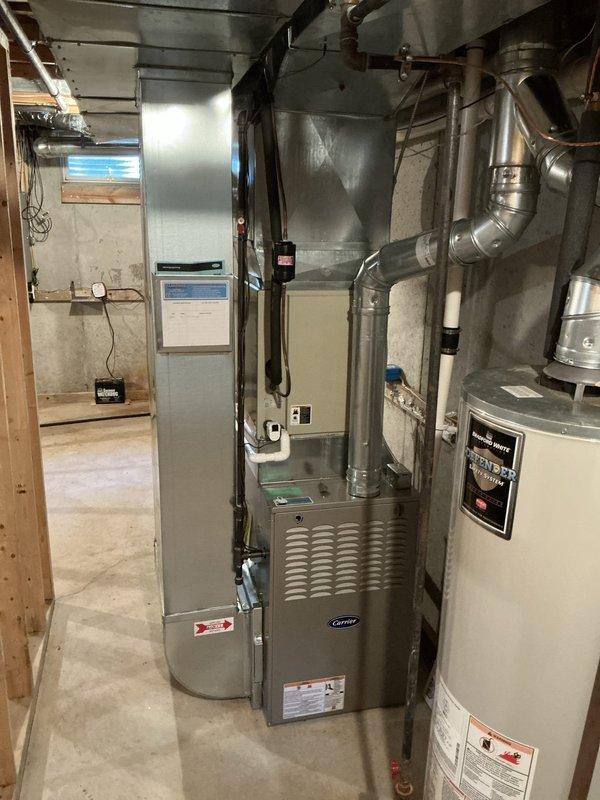 Completed estimate for residential air conditioning system evaluation in basement mechanical room. Homeowner expressed concerns about AC unit potentially being undersized and nearing end of service life. Inspection revealed existing Carrier furnace with connected ductwork and separate cooling system components; confirmed previous service records show furnace replacement only, while AC unit remains original to home. Documented current equipment configuration, ductwork layout, and system specifications with photos for estimate preparation. Applied veteran discount to proposed replacement options.