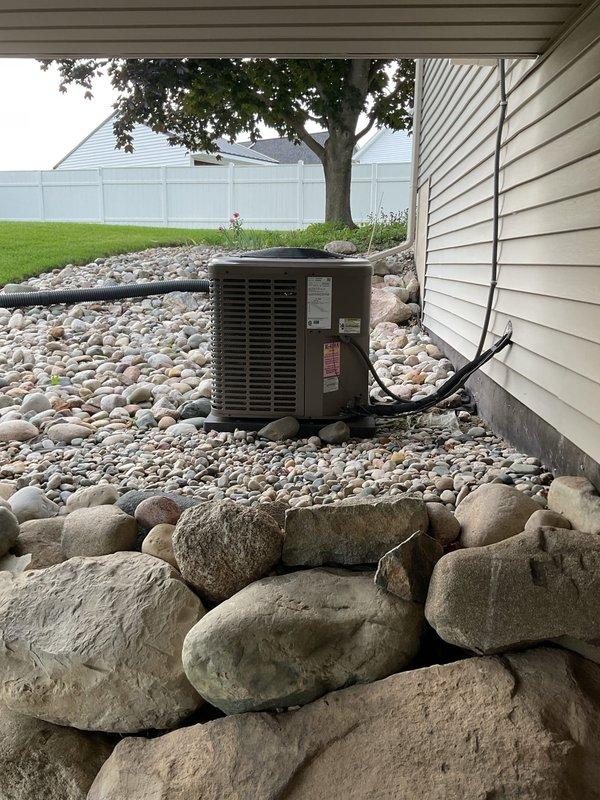 Responded to no cooling call on 12-year-old York system. Upon inspection, diagnosed leaking evaporator coil in indoor air handler unit located in basement mechanical room and confirmed outdoor condenser unit operational status. Documented equipment condition with photos of both outdoor condensing unit positioned on decorative rock bed against residence and indoor air handler cabinet with associated refrigerant piping and drainage lines. Provided estimate for evaporator coil replacement and related repairs necessary to restore system functionality.
