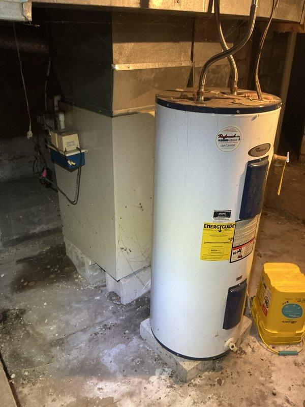 Responded to no cooling complaint on 15-year-old Bryant Plus 90 system. Upon arrival, confirmed blower motor failure preventing air circulation. Inspected furnace installation in basement utility area, noting unit positioned against stone foundation with standard PVC venting configuration. Diagnosed inoperative blower motor as primary cause of system failure. Documented equipment condition and installation setup including associated water heater and mechanical room layout for service records.