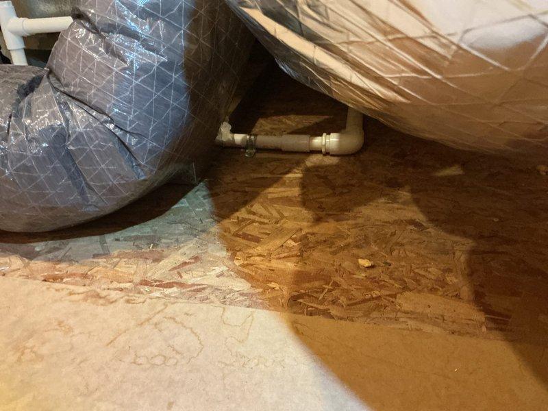 # CP-Cooling Problem Resolution

Responded to service call for air conditioning system not cooling to set temperature with water accumulation in drain pan. Upon inspection, identified condensate drainage issue affecting system performance. Located condensate drain line assembly in crawl space showing signs of blockage and improper drainage. Examined PVC drain piping configuration with visible discoloration and staining around joint connections, indicating chronic moisture problems and potential biofilm buildup restricting flow.

Cleared condensate line obstruction and verified proper drainage function. Inspected drain pan for cracks or damage. Tested system operation and confirmed air conditioning unit now cooling properly to set temperature with condensate draining freely through cleaned drain line. System restored to normal operation with proper drainage function established.