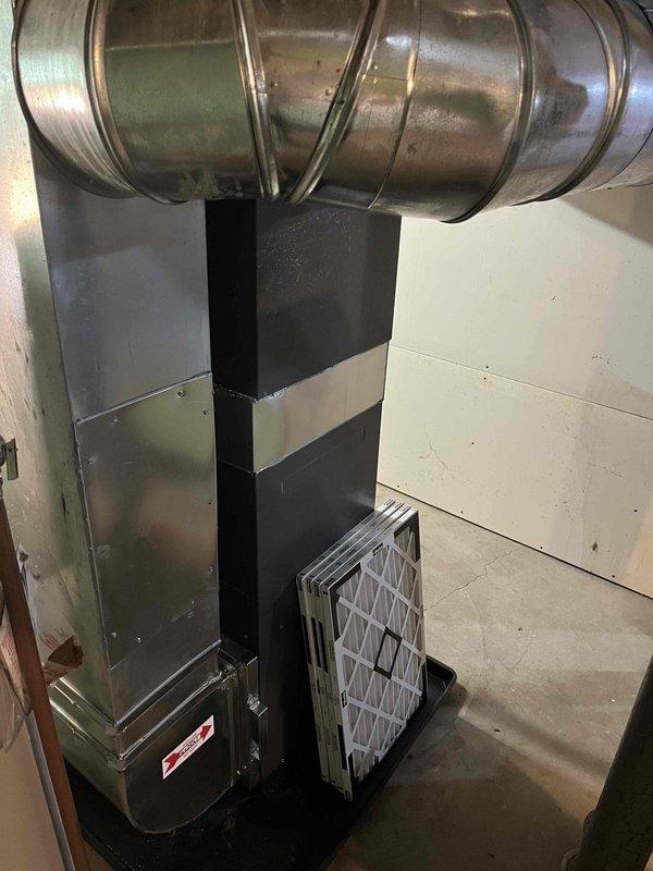 Completed full furnace installation in basement utility area. Installed new forced-air heating system with proper venting configuration using white PVC intake and exhaust pipes, connected metallic ductwork and flexible ducting to distribution system, and positioned evaporator coil assembly for integration with existing air conditioning components. System tested and confirmed operational with all safety labels and specifications visible, air filter properly installed, and all electrical and gas connections secured per manufacturer requirements.
