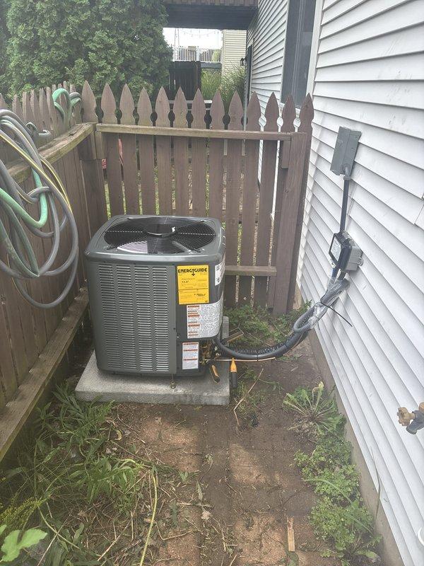 Completed full HVAC system installation including new furnace and air conditioning condenser unit. Furnace installed in interior utility space with proper metallic supply ductwork and PVC condensate drainage system. Exterior AC condenser positioned on concrete pad in side yard with insulated refrigerant lines, electrical conduit, and disconnect box properly mounted to exterior wall per code requirements.