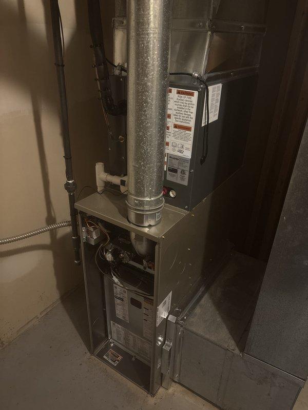 Completed full HVAC system installation including new furnace and air conditioning condenser unit. Furnace installed in interior utility space with proper metallic supply ductwork and PVC condensate drainage system. Exterior AC condenser positioned on concrete pad in side yard with insulated refrigerant lines, electrical conduit, and disconnect box properly mounted to exterior wall per code requirements.