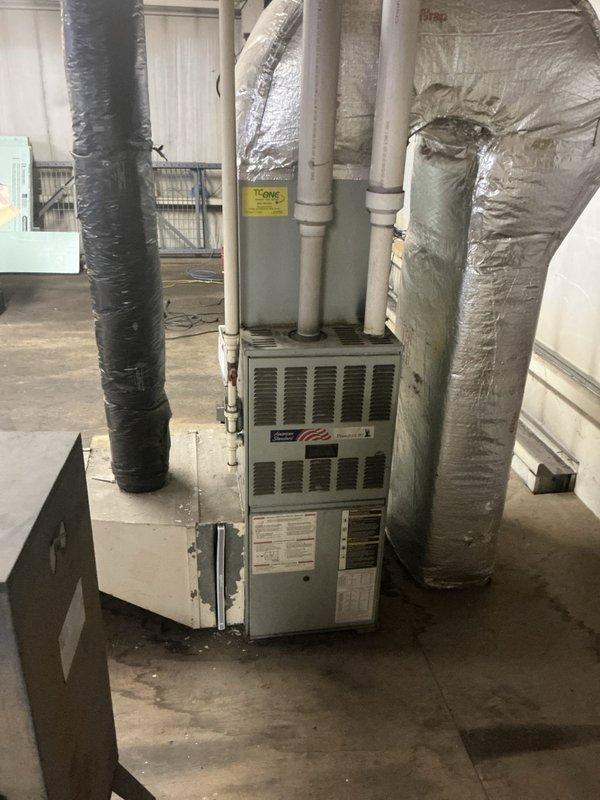 Performed comprehensive estimate for non-operational residential air conditioning system with ground-level outdoor condensing unit and basement furnace installation. Documented existing equipment conditions including beige condensing unit positioned on river rock landscaping bed against exterior wall, and basement furnace with multiple insulated ductwork configurations in black and silver wrapping. Assessed system components, photographed equipment placement and mechanical connections, and prepared detailed estimate for repair or replacement options to restore cooling functionality.
