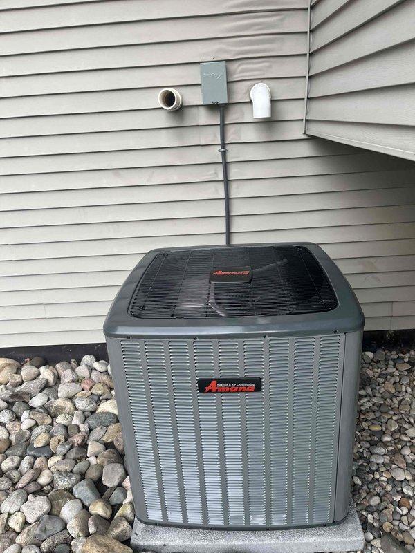 Completed full HVAC system installation including indoor furnace/air handler unit and outdoor Amana condensing unit. Installed furnace in basement utility area with proper ductwork connections, PVC condensate drainage system, and electrical conduit. Mounted outdoor condenser on concrete pad against exterior wall with appropriate clearances, connected refrigerant lines, installed electrical service disconnect, and completed PVC drainage piping through exterior wall. System tested and verified operational upon completion.