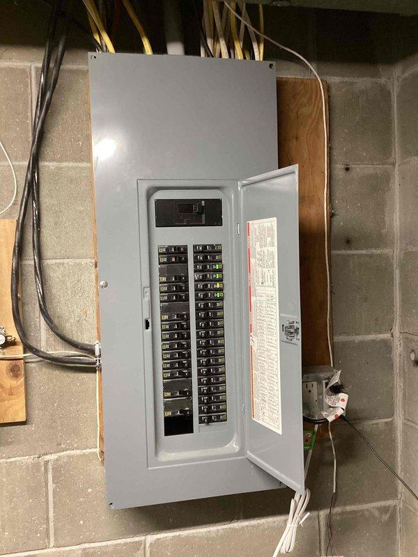 Conducted on-site assessment for generator installation estimate. Evaluated existing electrical infrastructure including main circuit breaker panel in basement utility area and attic wiring configuration. Documented current electrical service capacity, available breaker spaces, and wire routing paths to determine optimal generator integration point. Photographed existing panel layout showing dual-row breaker arrangement with main disconnect, as well as overhead electrical distribution system with bundled residential wiring including multiple circuits running along ceiling joists. Assessment included verification of suitable mounting location for transfer switch and evaluation of conduit pathways for generator connection to existing electrical system.