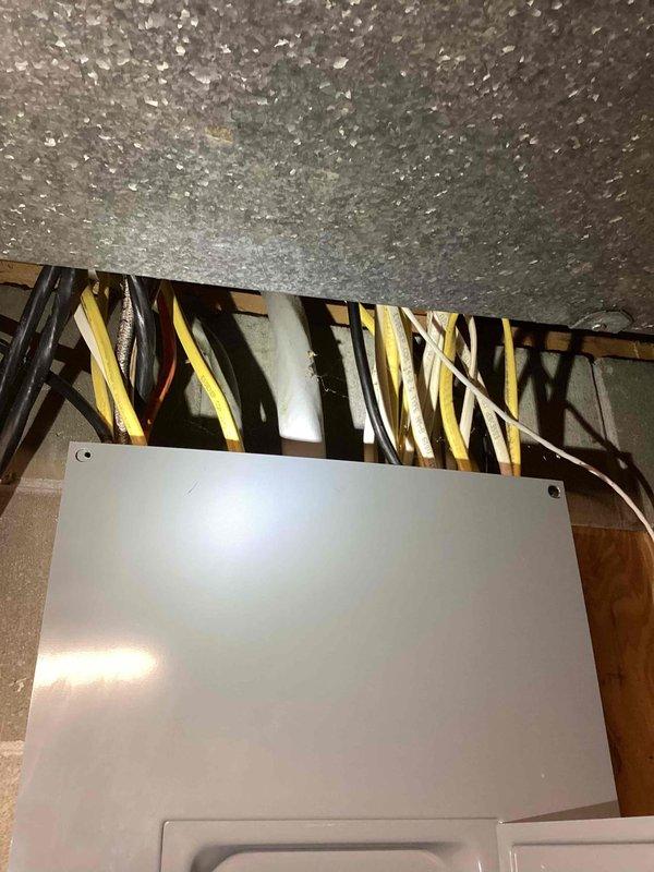 Conducted on-site assessment for generator installation estimate. Evaluated existing electrical infrastructure including main circuit breaker panel in basement utility area and attic wiring configuration. Documented current electrical service capacity, available breaker spaces, and wire routing paths to determine optimal generator integration point. Photographed existing panel layout showing dual-row breaker arrangement with main disconnect, as well as overhead electrical distribution system with bundled residential wiring including multiple circuits running along ceiling joists. Assessment included verification of suitable mounting location for transfer switch and evaluation of conduit pathways for generator connection to existing electrical system.
