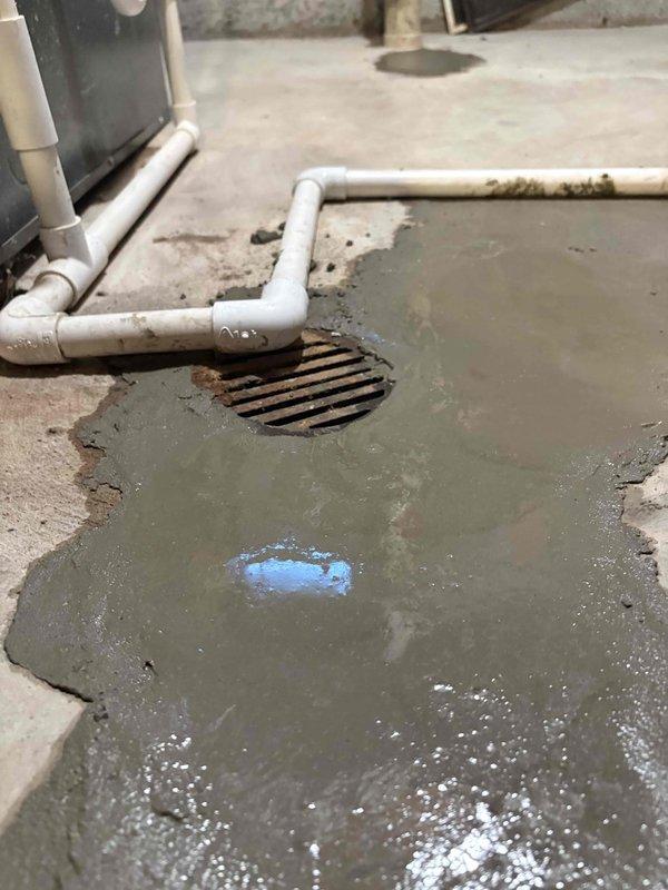 Responded to standing water issue in basement utility area. Poured and applied fresh concrete/cement around brass pipe base to seal floor penetration and prevent water infiltration. Completed repair work around floor drain area where moisture accumulation was evident.