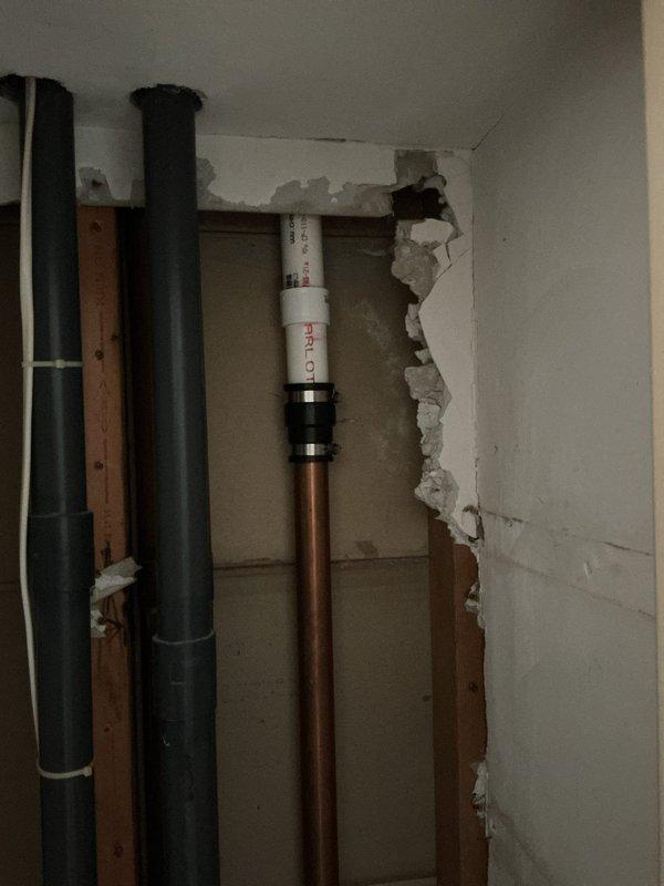 # Copper Drain Line Replacement

Replaced deteriorated copper drain line in residential property. Accessed plumbing system by opening ceiling in hallway corridor and wall cavity to expose vertical pipe runs. Removed damaged copper drain line and installed new drainage piping with proper support clamps and mounting brackets. Installed PRO-series plumbing components with secure fittings to ensure code-compliant installation. All connections tested for proper drainage flow and leak-free operation prior to closing work areas.