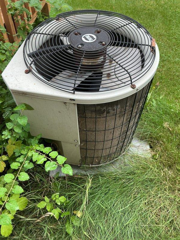 Responded to service call for 15-year-old residential air conditioning system with inadequate cooling and reported water leak in basement. Upon arrival, found air handler operational with blower circulating air through ductwork, but insufficient temperature drop across system. Inspected outdoor condenser unit and identified signs of weathering and dirt accumulation on exterior panels and coil surfaces. Assessed condensate drainage system and located source of basement leak related to AC operation. Performed diagnostic testing to determine root cause of cooling deficiency and documented equipment condition through photographic documentation of outdoor unit positioning, installation configuration, and surrounding environment.