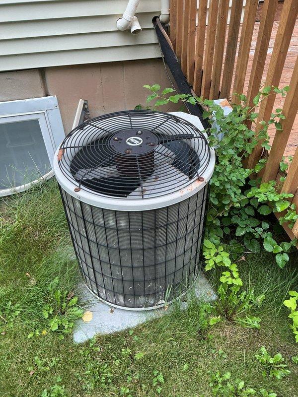 Responded to service call for 15-year-old residential air conditioning system with inadequate cooling and reported water leak in basement. Upon arrival, found air handler operational with blower circulating air through ductwork, but insufficient temperature drop across system. Inspected outdoor condenser unit and identified signs of weathering and dirt accumulation on exterior panels and coil surfaces. Assessed condensate drainage system and located source of basement leak related to AC operation. Performed diagnostic testing to determine root cause of cooling deficiency and documented equipment condition through photographic documentation of outdoor unit positioning, installation configuration, and surrounding environment.