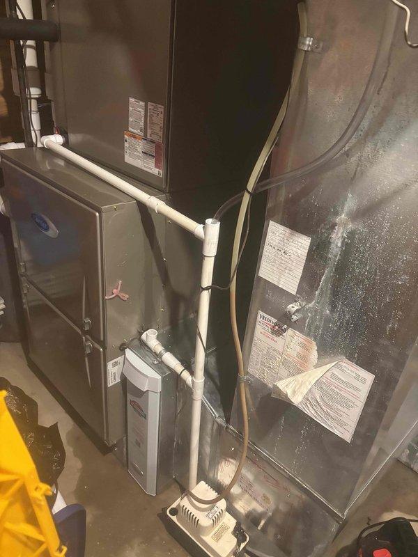 Responded to water leak service call in basement utility area. Upon arrival, found significant water accumulation on concrete floor adjacent to 21-year-old Carrier furnace and water heater. Inspected HVAC system and identified source of leak as failed condensate drainage system. Condensate pump appeared non-functional, causing water to overflow onto floor rather than properly draining. Documented conditions with photos showing extent of water damage and equipment involved. Recommended repair or replacement of condensate pump and proper drainage system restoration to prevent future water accumulation and potential damage to furnace and surrounding area.
