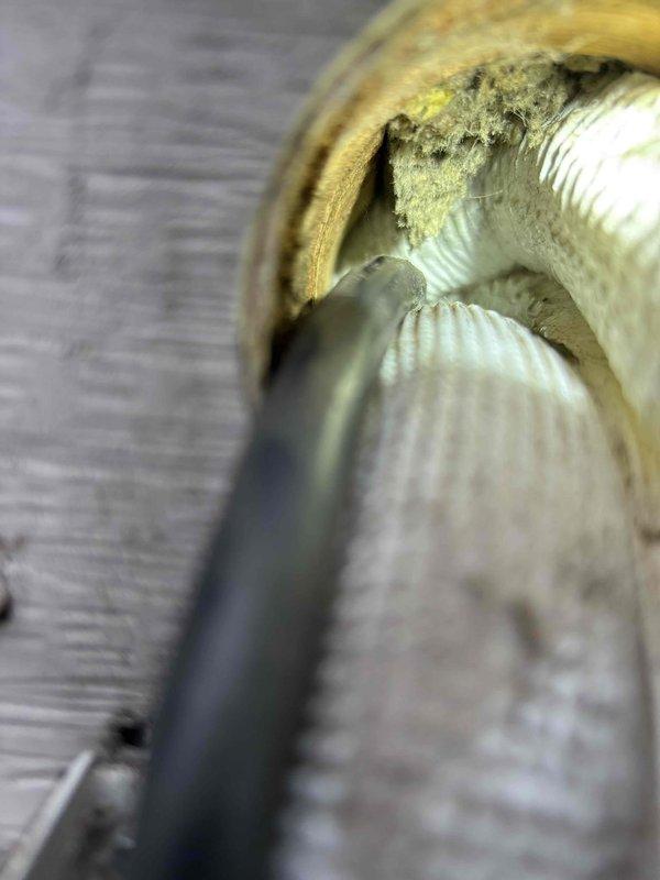 Responded to water leak complaint on Fujitsu mini split system. Upon inspection, found deteriorated foam insulation on refrigerant line set with significant gap allowing condensate accumulation and dark debris buildup around exposed piping. Documented condition of both interior insulated piping and exterior wall penetration where line set passes through siding, noting aged and discolored insulation requiring replacement to prevent continued moisture issues.