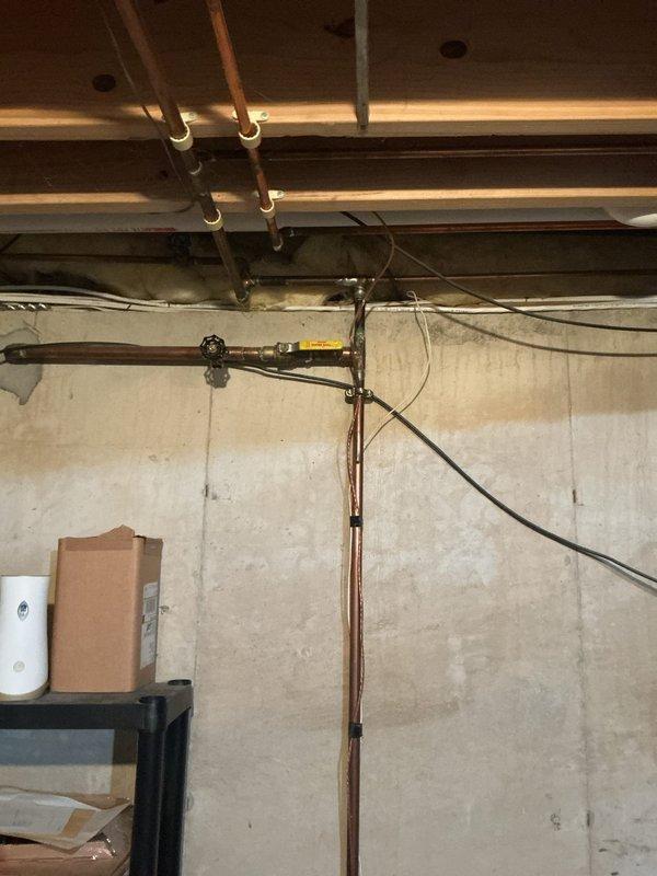 Conducted on-site assessment for installation of automatic shut-off valve on main water line entering residence. Evaluated existing copper piping configuration in basement utility area, documenting current plumbing infrastructure including main water supply line routing from entry point through ceiling joists and vertical drop to distribution system. Photographed installation location showing accessible main line with adequate clearance for valve placement and identified optimal mounting position on vertical copper supply pipe near point of entry to ensure effective whole-house water control capability.