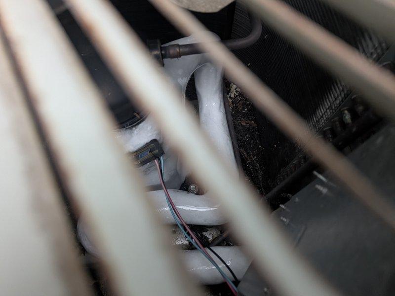 Responded to no cooling complaint on 26-year-old International Comfort Products system. Found outdoor condenser fan operational but unit not producing cool air. Inspected indoor air handler components including condensate pump and drainage system, which appeared functional. Evaluated outdoor unit installation and refrigerant line insulation at exterior wall penetration. System requires further diagnostic testing to determine root cause of cooling failure, likely involving refrigerant charge verification, compressor operation assessment, or potential airflow restrictions.