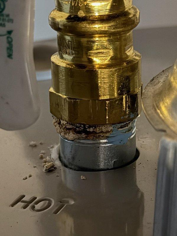 Responded to service call for water heater with corroding supply lines. Upon inspection, documented significant corrosion and mineral buildup on brass fittings at hot water connection point, with white and brown crusty deposits indicating active deterioration at dissimilar metal junctions. Photographed affected components showing advanced oxidation and mineral accumulation on threaded connections and mounting surfaces to document condition for replacement recommendations.