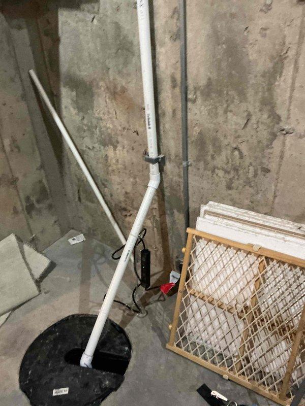 # Tankless Water Heater Installation Estimate

Conducted comprehensive site assessment for replacement of existing conventional hot water tank with tankless water heater system in residential basement utility area. Evaluated existing plumbing infrastructure including vertical PVC drainage lines, copper supply piping, and electrical connections at installation location. Documented current conditions showing concrete foundation walls with moisture exposure indicators, existing utility connections, and available clearances for equipment placement. Assessed venting requirements, gas line accessibility, and electrical service capacity for tankless unit installation. Photographed mechanical space configuration including floor-to-ceiling plumbing runs, junction boxes, and structural elements to determine optimal mounting location and connection points. Provided detailed project estimate for complete removal of existing water heater and installation of new tankless system with necessary modifi