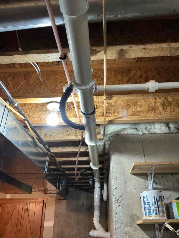 # Tankless Water Heater Installation Estimate

Conducted comprehensive site assessment for replacement of existing conventional hot water tank with tankless water heater system in residential basement utility area. Evaluated existing plumbing infrastructure including vertical PVC drainage lines, copper supply piping, and electrical connections at installation location. Documented current conditions showing concrete foundation walls with moisture exposure indicators, existing utility connections, and available clearances for equipment placement. Assessed venting requirements, gas line accessibility, and electrical service capacity for tankless unit installation. Photographed mechanical space configuration including floor-to-ceiling plumbing runs, junction boxes, and structural elements to determine optimal mounting location and connection points. Provided detailed project estimate for complete removal of existing water heater and installation of new tankless system with necessary modifi
