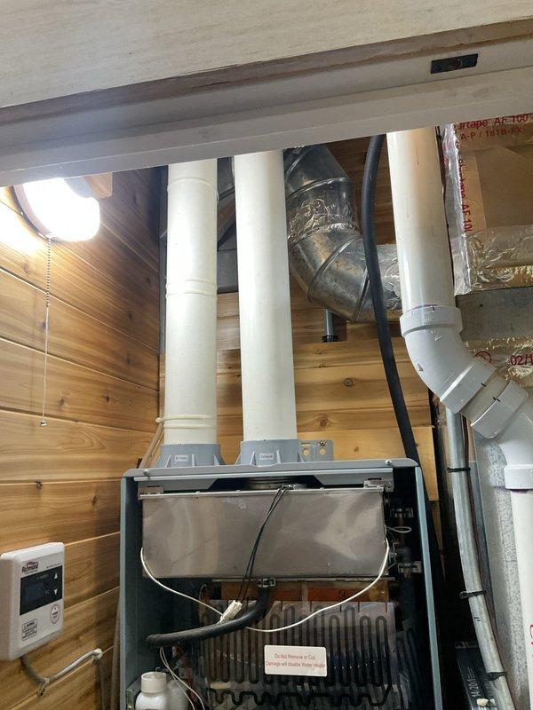 Responded to service call for 8-year-old Richmond tankless water heater with no hot water production. Upon arrival, accessed unit's internal components by removing front panel to diagnose heating failure. Inspected heat exchanger assembly, control board, electrical connections, and wiring harness for potential faults. Examined venting system including intake and exhaust PVC piping for proper configuration and blockages. Documented internal component condition including circuit board, wire connections, and heat exchanger coils through photographic evidence. Completed diagnostic assessment of non-operational tankless water heating system.