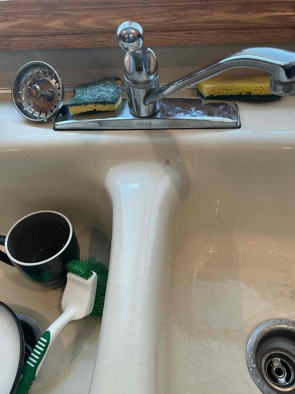 Responded to plumbing leak complaint where upstairs shower was leaking through to the main floor below when in use. Inspected shower control valve assembly and surrounding wall area for signs of water intrusion. Examined chrome trim plate, single-handle lever control, and tub spout fixture, noting aged condition with mineral deposits and water spots indicating ongoing moisture exposure. Assessed valve seals, cartridge, and wall penetration points as potential leak sources. Documented fixture condition and surrounding areas to determine source of water migration to lower level.