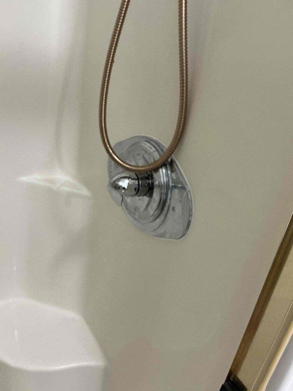 Completed shower valve replacement in bathroom. Removed existing fixture and installed new chrome-plated shower arm with wall flange, ensuring proper threading and seal to prevent leaks. Connected flexible metal supply hose to new valve assembly and verified water flow and temperature control functionality upon completion.