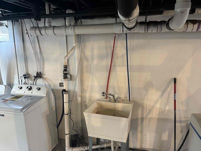 Responded to washer drain backing up into utility sink. Upon arrival, found slow drainage from washing machine discharge causing water to overflow into adjacent laundry basin. Cleared obstruction in shared drain line using appropriate drain cleaning equipment. Tested system by running water through washer drain and utility sink simultaneously to verify proper flow and drainage. System now operating normally with no backup issues.