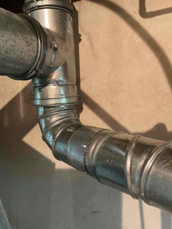 Responded to emergency inspector correction for rotted water heater connector pipe at chimney tie-in point causing carbon monoxide detector activation. Replaced deteriorated 4-inch galvanized connector pipe and elbow fitting showing severe corrosion and oxidation. Secured all connections with proper clamps and verified proper venting to eliminate CO hazard.