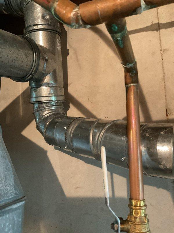 Responded to emergency inspector correction for rotted water heater connector pipe at chimney tie-in point causing carbon monoxide detector activation. Replaced deteriorated 4-inch galvanized connector pipe and elbow fitting showing severe corrosion and oxidation. Secured all connections with proper clamps and verified proper venting to eliminate CO hazard.