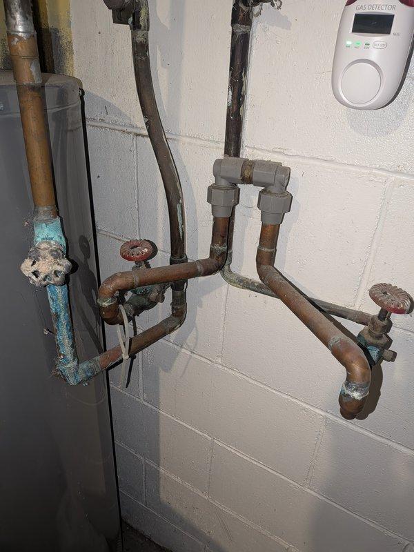 Responded to service call for 9-year-old Rheem water heater experiencing insufficient heating and unusual bubbling sounds. Upon inspection, found extensive corrosion on water supply piping and shutoff valves, indicating long-term moisture exposure and mineral buildup. Documented deteriorated plumbing components and water heater connections showing rust and scale accumulation consistent with sediment buildup in tank, which typically causes reduced heating efficiency and bubbling noises during operation.