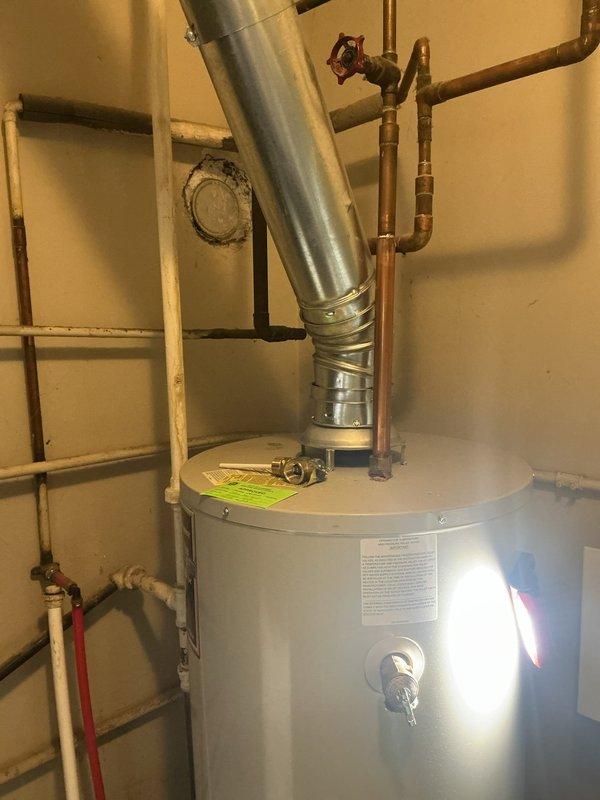 Responded to service call for water heater not producing hot water. Inspected Bradford white water heater unit and verified temperature and pressure relief valve operation, examined all plumbing connections including copper supply lines and red valve assembly at top of tank. Tested temperature control dial functionality and checked flue vent system for proper installation and secure mounting. Documented unit condition with photos showing valve connections, TPR valve with blue indicator, and overall installation including copper piping configuration and exhaust venting. All connections inspected and system evaluated for proper operation.