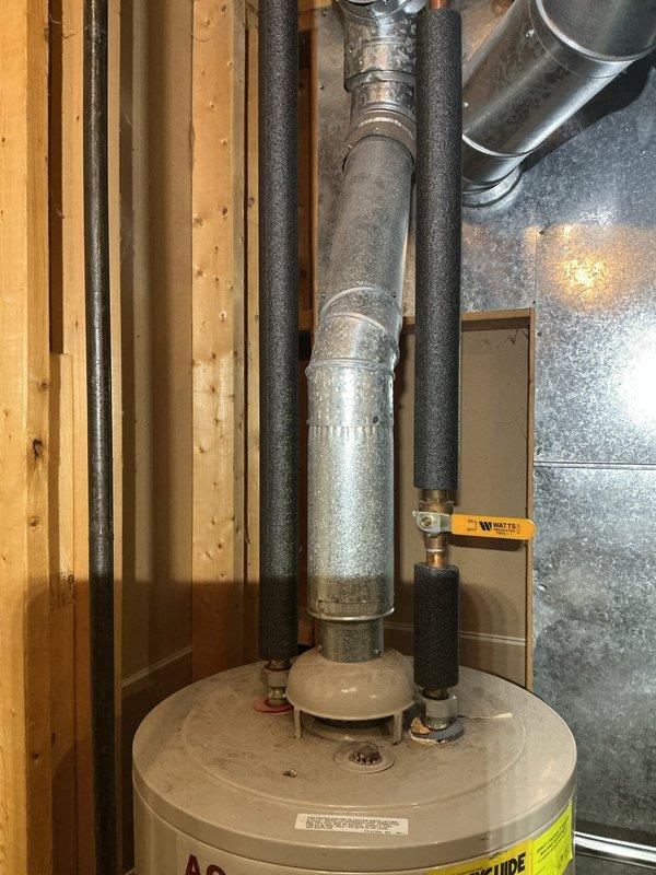 Responded to water leak originating from water heater installed in the 1990s. Upon inspection, found active leaking underneath the unit, which had exceeded its typical service life. Documented existing installation showing water heater with associated plumbing, flue pipe, and insulated supply lines in basement utility area. Recommended water heater replacement due to age and leak condition to prevent further water damage and ensure safe operation of domestic hot water system.