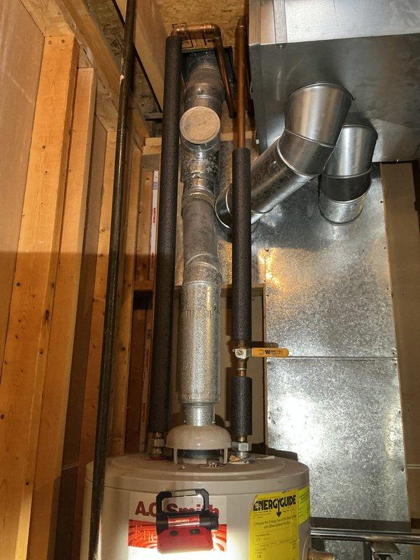 Responded to water leak originating from water heater installed in the 1990s. Upon inspection, found active leaking underneath the unit, which had exceeded its typical service life. Documented existing installation showing water heater with associated plumbing, flue pipe, and insulated supply lines in basement utility area. Recommended water heater replacement due to age and leak condition to prevent further water damage and ensure safe operation of domestic hot water system.