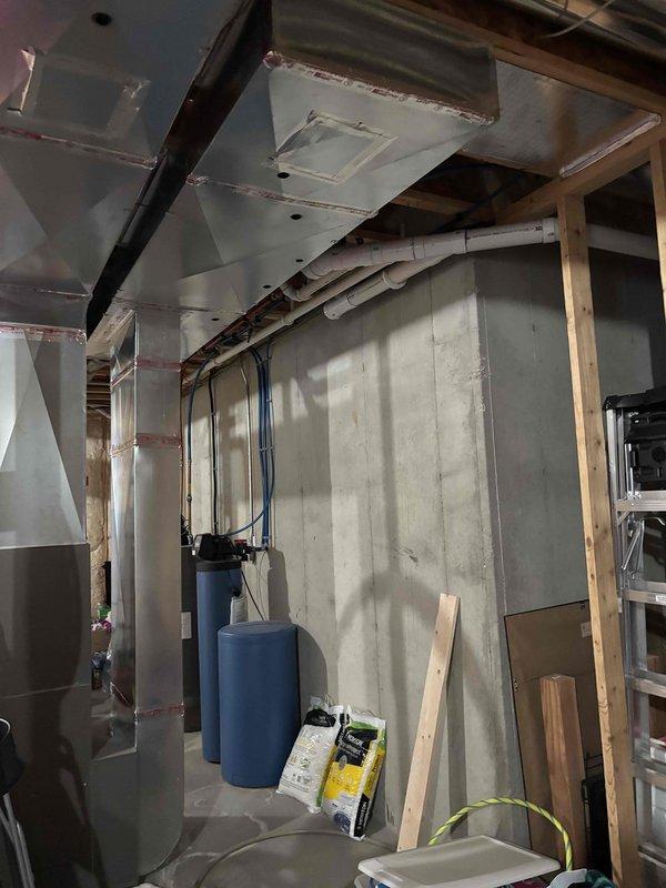 Conducted electrical estimate for EV charging installation in garage, troubleshooting of malfunctioning light switches in garage, and assessment of electrical concerns in unfinished basement area. Inspected existing electrical panel with exposed circuit breakers and evaluated current wiring configuration, noting multiple branch circuits and available capacity for potential EV charger load requirements. Documented basement electrical infrastructure including panel location within framed stud walls, existing conduit runs, and proximity to mechanical equipment including water treatment systems and HVAC ductwork for coordination of future electrical work.