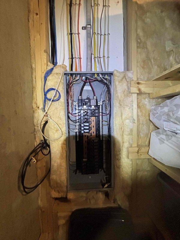 Conducted electrical estimate for EV charging installation in garage, troubleshooting of malfunctioning light switches in garage, and assessment of electrical concerns in unfinished basement area. Inspected existing electrical panel with exposed circuit breakers and evaluated current wiring configuration, noting multiple branch circuits and available capacity for potential EV charger load requirements. Documented basement electrical infrastructure including panel location within framed stud walls, existing conduit runs, and proximity to mechanical equipment including water treatment systems and HVAC ductwork for coordination of future electrical work.