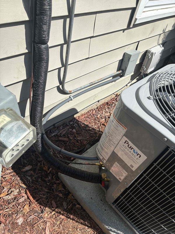 Completed full air conditioning system replacement with installation of new Rheem condensing unit on exterior concrete pad. Installed R-454B refrigerant system with proper initial charge, connected refrigerant line sets with brass fittings and black insulated tubing, and secured all electrical connections and conduit to building exterior. System activated and verified operational per manufacturer specifications.