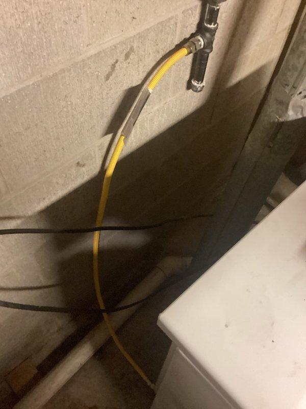 Completed project estimate for replacement of existing flexible gas line supplying clothes dryer in basement utility area. Current installation utilizes yellow CSST (Corrugated Stainless Steel Tubing) running from rigid black iron pipe connection at wall down to dryer location. Assessment identified need to replace deteriorated gas line and associated shut-off valve fitting. Documented existing conditions showing gas line routing along concrete block walls with connection points requiring updated components to meet current code requirements and ensure safe operation of gas-fired appliance.