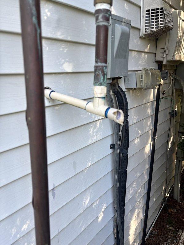 Responded to plumbing leak emergency in basement where water distribution system splits to two meters. Repaired leaking copper union connection at the split point, addressing significant corrosion and oxidation on aged copper piping. Additionally, repaired leaking elbow joint on exterior where plumbing transitions from house through wall to outdoor system, ensuring proper seal and connection integrity at the penetration point. Both leaks were stopped and system restored to proper operation.