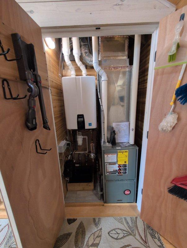 Completed same-day installation of new tankless water heater system in residential utility closet. Removed existing water heating equipment and installed wall-mounted tankless unit with proper venting using white PVC piping, integrated copper and PVC supply lines with brass fittings and shutoff valves, and installed pressure regulation and filtration components. All plumbing connections tested and verified for proper operation, unit programmed and commissioned per manufacturer specifications.