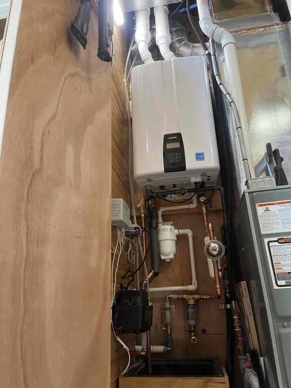 Completed same-day installation of new tankless water heater system in residential utility closet. Removed existing water heating equipment and installed wall-mounted tankless unit with proper venting using white PVC piping, integrated copper and PVC supply lines with brass fittings and shutoff valves, and installed pressure regulation and filtration components. All plumbing connections tested and verified for proper operation, unit programmed and commissioned per manufacturer specifications.