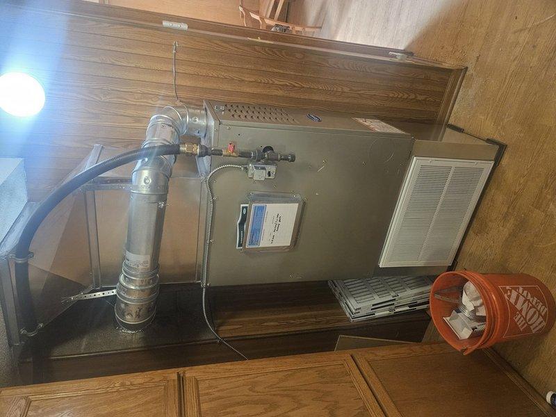 Completed full furnace replacement in residential utility closet. Removed existing unit and installed new beige metal cabinet-style furnace with integrated air handler. Connected metallic combustion vent pipe and blue flexible ductwork to main distribution system. Installed and configured gas valve assembly with copper fittings, electrical connections, and control wiring. Verified proper ventilation grille operation and secured all ductwork connections. Tested system startup, confirmed proper combustion, airflow, and safety controls functioning within manufacturer specifications.