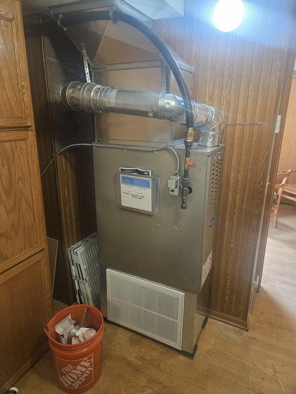 Completed full furnace replacement in residential utility closet. Removed existing unit and installed new beige metal cabinet-style furnace with integrated air handler. Connected metallic combustion vent pipe and blue flexible ductwork to main distribution system. Installed and configured gas valve assembly with copper fittings, electrical connections, and control wiring. Verified proper ventilation grille operation and secured all ductwork connections. Tested system startup, confirmed proper combustion, airflow, and safety controls functioning within manufacturer specifications.