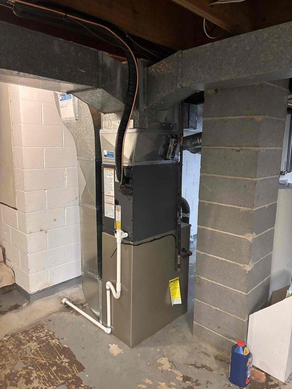 Completed full HVAC system replacement in basement mechanical room. Removed existing equipment and installed new Carrier furnace unit with complete ductwork configuration including metal trunk lines and branch ducts connected to ceiling joists. Installed PVC condensate drainage system with proper routing along unit exterior. Configured supply and return air ductwork with rigid metal and flexible duct components to ensure optimal airflow distribution throughout residence. All equipment positioned between concrete block walls with proper clearances maintained for service access and code compliance. System tested and verified operational upon completion.