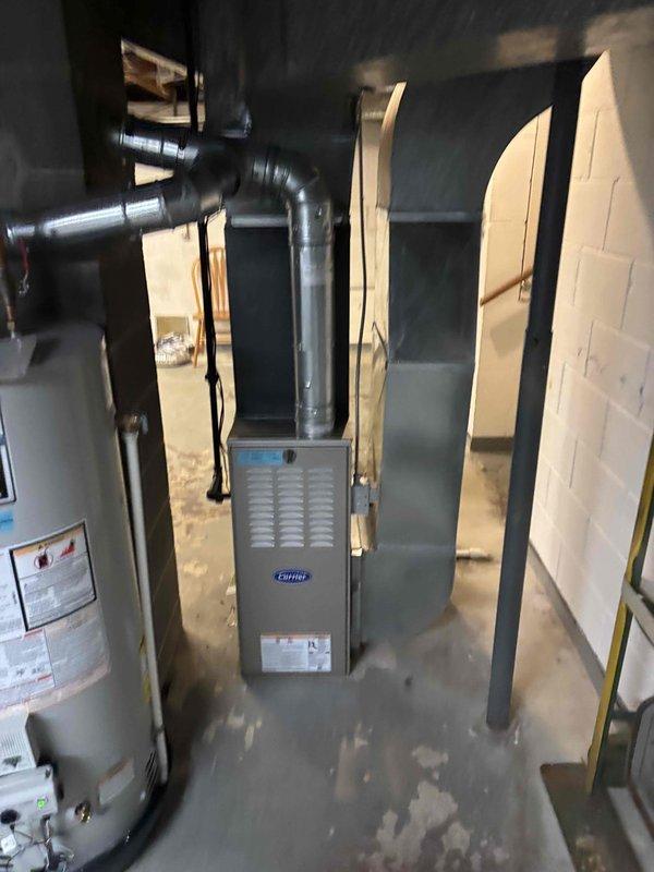 Completed full HVAC system replacement in basement mechanical room. Removed existing equipment and installed new Carrier furnace unit with complete ductwork configuration including metal trunk lines and branch ducts connected to ceiling joists. Installed PVC condensate drainage system with proper routing along unit exterior. Configured supply and return air ductwork with rigid metal and flexible duct components to ensure optimal airflow distribution throughout residence. All equipment positioned between concrete block walls with proper clearances maintained for service access and code compliance. System tested and verified operational upon completion.