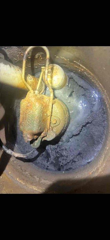 Responded to service call for malfunctioning sump pump that was backing up constantly over the past week and only draining when physically agitated. Upon inspection, found heavily corroded pump components with significant mineral buildup and oxidation on brass fittings, indicating extended exposure to moisture and lack of maintenance. Assessed pump mechanism, check valve assembly, and float switch operation. Relocated utility sink as requested to improve basement utility room layout and accessibility. Documented existing conditions with photos showing deteriorated pump hardware and overall plumbing configuration including PVC drainage system and utility fixtures.