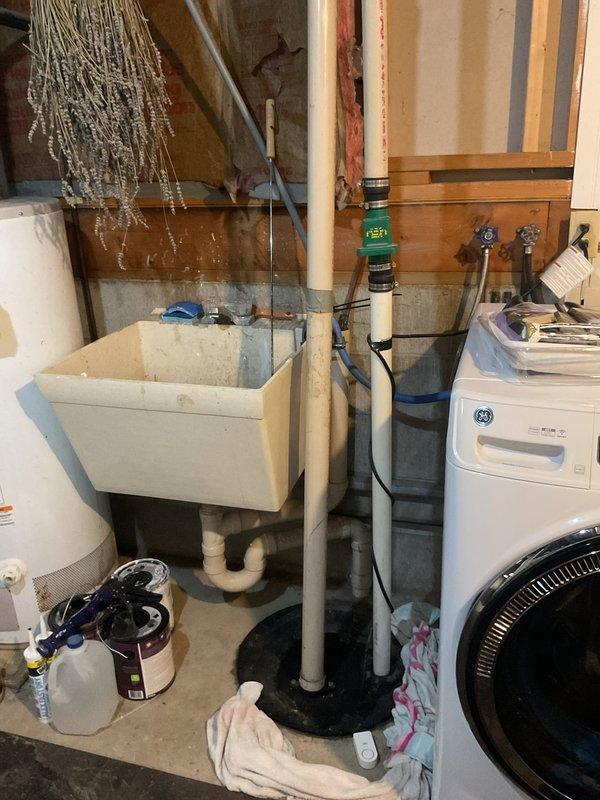 Responded to service call for malfunctioning sump pump that was backing up constantly over the past week and only draining when physically agitated. Upon inspection, found heavily corroded pump components with significant mineral buildup and oxidation on brass fittings, indicating extended exposure to moisture and lack of maintenance. Assessed pump mechanism, check valve assembly, and float switch operation. Relocated utility sink as requested to improve basement utility room layout and accessibility. Documented existing conditions with photos showing deteriorated pump hardware and overall plumbing configuration including PVC drainage system and utility fixtures.
