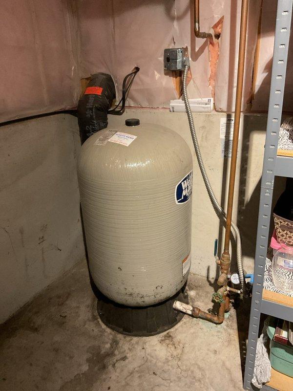 Responded to report of active leak at pressure tank system. Upon arrival, conducted thorough inspection of the water pressure tank, bladder assembly, and associated pressure pump components. Examined all visible plumbing connections, fittings, and copper piping for signs of moisture, corrosion, or active leakage. Tested pressure gauge operation and verified system pressure readings. Inspected tank exterior for integrity issues and checked bladder function through standard diagnostic procedures. Evaluated pump operation and cycling performance. Documented equipment condition through photographic evidence showing tank installation, piping configuration, and surrounding utility area. Identified source of reported leak and provided assessment of overall system condition.