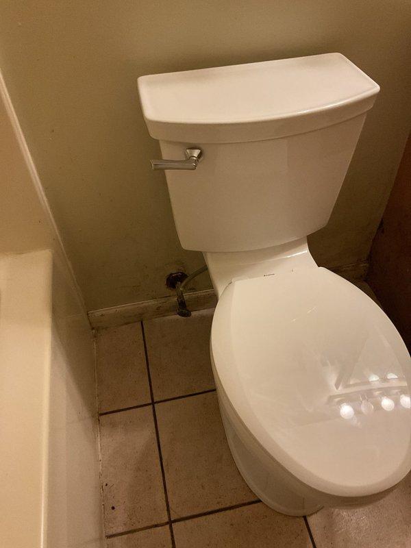 Completed toilet replacement in residential bathroom. Removed existing two-piece toilet and installed new white porcelain two-piece unit with chrome flush lever, ensuring proper positioning, secure mounting, and connection to water supply line. Verified functionality and confirmed no leaks upon completion.