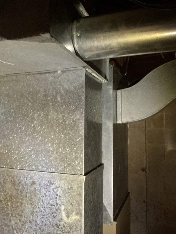 Completed estimate for replacement of aging but operational furnace and air conditioning system. Inspected existing equipment in basement mechanical room, including vertical furnace unit with front-mounted ventilation grilles and PVC exhaust piping, along with associated ductwork in confined mechanical space above. Documented current system configuration through photographs showing galvanized metal supply and return ductwork, cylindrical ventilation components, and overall equipment condition to provide accurate replacement recommendations for updated HVAC system.